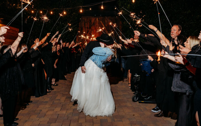 Bride and groom kissing in front of a crowd of their closest friends holding sparklers